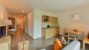 A compact living space with a kitchenette, a dining area, and a seating area with a sofa and chairs. - Chalet in the Alpine Lodge Klösterle (Klösterle am Arlberg)
