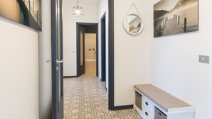 Un pasillo con piso estampado, un espejo en la pared y obras de arte.