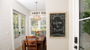 Un coin repas avec une table et des chaises en bois, un luminaire suspendu et un panneau noir sur lequel on peut lire : « Bienvenue chez Breville ».