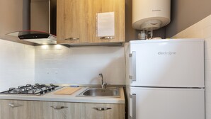 A modern kitchen with a gas stove, stainless steel sink, and a white refrigerator.