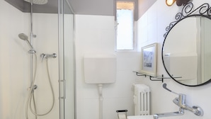 A modern bathroom with a glass shower enclosure, a toilet, a sink, and a mirror with a decorative frame.