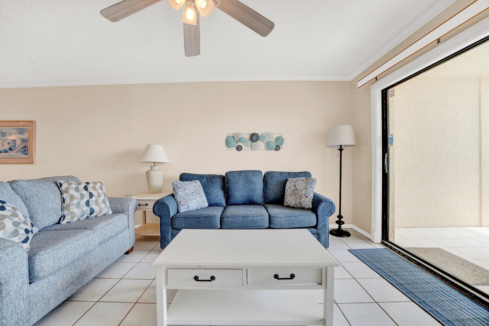 A living room with a blue sofa, white coffee table, and a ceiling fan.