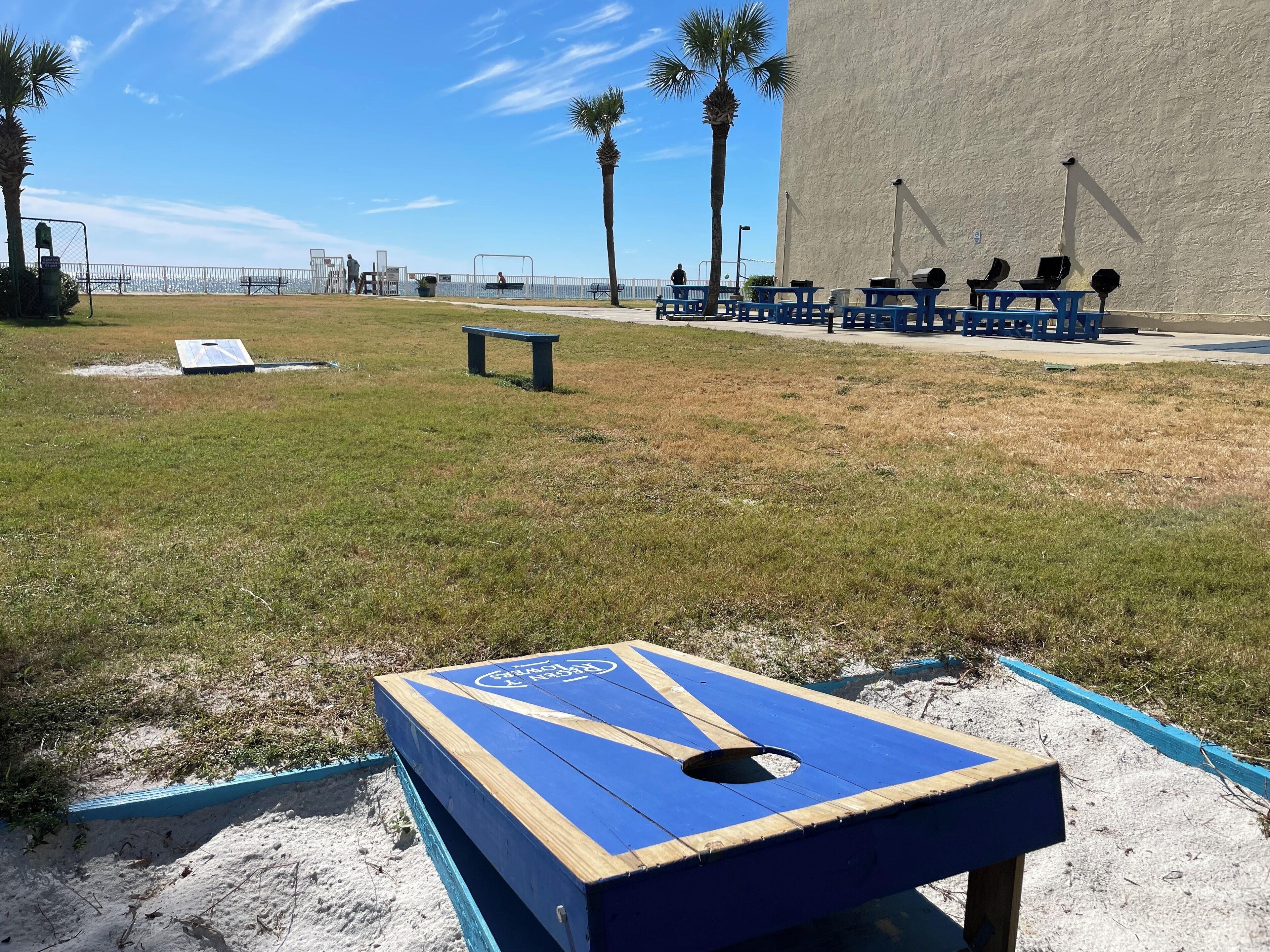 A beachside area with a blue and wooden structure, a fenced walkway, and benches.