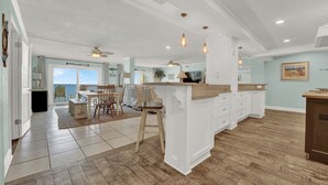 Un'ampia cucina con una grande isola, pavimento in legno e illuminazione a sospensione.