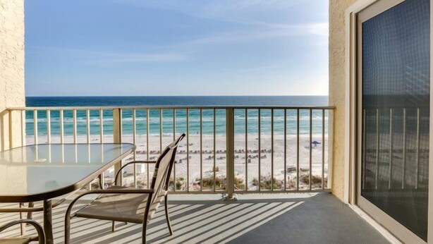 A balcony with a glass table and chairs overlooking a beach with a clear view of the ocean and distant shoreline. - 2 Bedroom Condo Oceanfront Paradise! (Panama City)