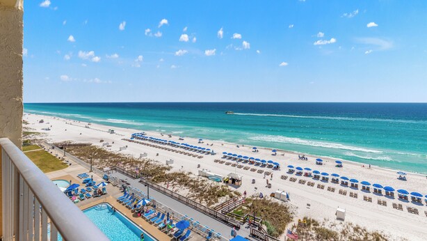 A beach resort with a pool, beach umbrellas, and lounge chairs.