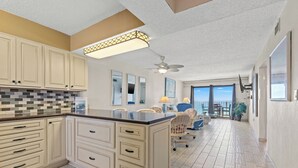 A spacious kitchen with a large island, white cabinetry, and a tiled backsplash.