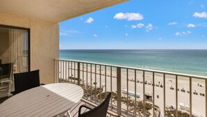A balcony with a view of the beach, a table, and chairs. - 2 Bedroom Deluxe Oceanfront with 2 Large Pool Facing Beautiful Beach (Panama City)