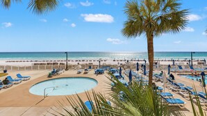 A pool area with lounge chairs, a palm tree, and a beach view. - 2bd/2ba Condo Ocean views from every room walk in shower FREE BEACH CHAIRS (PCB)