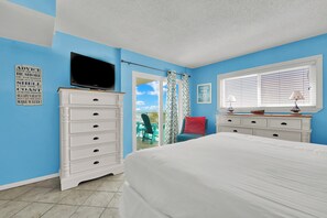 Un dormitorio con cama, cómoda, televisor y ventana con persianas.