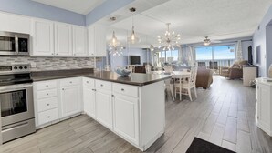 A modern kitchen with white cabinetry, a central island, stainless steel appliances, and pendant lighting. - 2bd/2ba Condo Ocean views from every room walk in shower FREE BEACH CHAIRS (Panama City Beach)