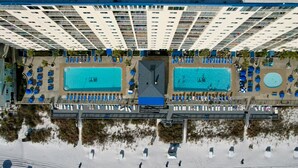 A resort with two swimming pools, a covered walkway, and beach huts.