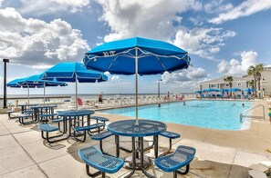 A poolside area with blue umbrellas and lounge chairs.