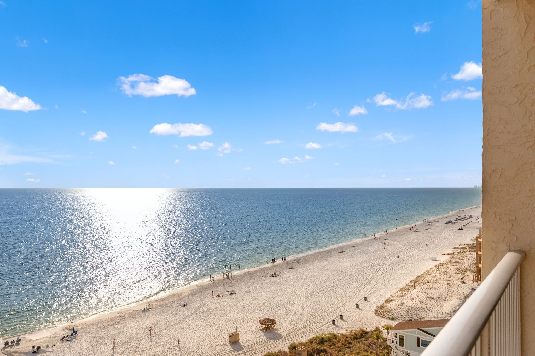 A beach view from a balcony with a clear sky and calm sea.