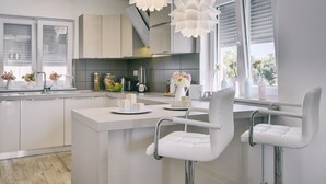 Una cocina moderna con armarios blancos, una isla central y lámparas colgantes.