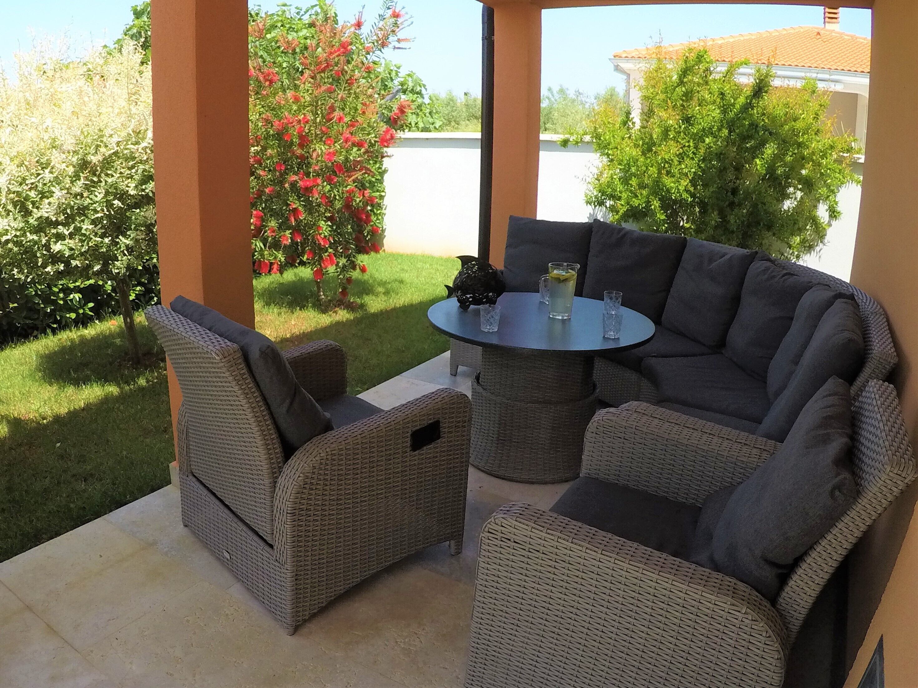 An outdoor patio with wicker furniture and a table.