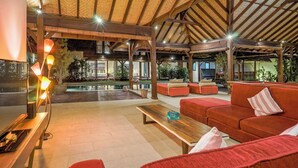 A spacious outdoor lounge area with a pool, red seating, and a wooden ceiling structure. - Large 5 bedroom villa with big pool - Seminyak (Seminyak)
