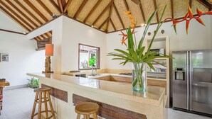 A kitchen with a central island, stools, a refrigerator, and a decorative plant. - Large 5 bedroom villa with big pool - Seminyak (Seminyak)