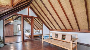 A spacious loft bedroom with a sloped ceiling, wooden beams, and a large window. - Large 5 bedroom villa with big pool - Seminyak (Seminyak)
