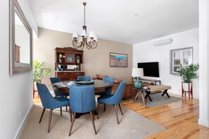 A dining area with a round table, blue chairs, a chandelier, and a wooden cabinet in the background. - By the Castle | STYLISH AND SPACIOUS | Family-Friendly (Lisboa)