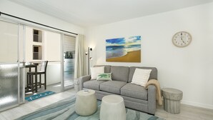 A living room with a grey sofa, a coffee table, and a round clock on the wall. - Modern condo in Heart of Waikiki! 1 block to beach, AC, Wi-Fi, free parking! (Honolulu)