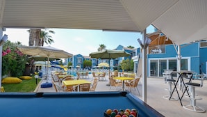 A pool area with multiple tables and chairs, umbrellas, and a pool table with balls. - BLUE PEARL HOTEL& VILLAS (Fethiye)