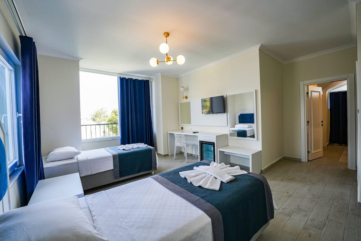 A hotel room with two beds, a desk, a chair, a TV, and a bathroom visible through an open door.