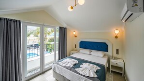 A hotel room with a large bed, a balcony with a pool view, and a modern ceiling light fixture. - BLUE PEARL HOTEL& VILLAS (Fethiye)