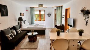 Relax in comfort with a comfortable bed, sofa, and dining area, offering a peaceful view of the outdoors.