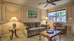 A living room with a beige sofa, a patterned armchair, a glass coffee table, and a ceiling fan. - Professional 2 Bedroom Condo on Singer Island, FL.  FREE parking.  Beach 5 min. (Singer Island)