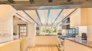 Una cocina moderna con suelo de madera, armarios blancos y horno empotrado.
