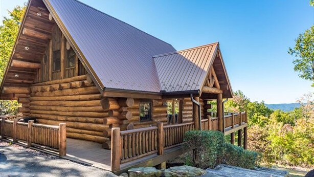 Eine Holzhütte mit einem Metalldach, einer Veranda und Blick auf die umliegende Landschaft.