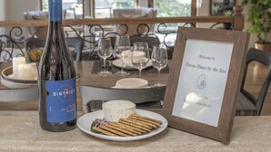 A bottle of District wine, a plate with crackers, and a framed welcome sign on a table.