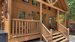 Une cabane en bois avec un porche, une enseigne indiquant le numéro « 854 » et une guirlande sur la porte.