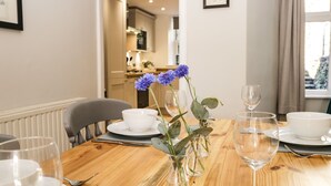 A dining table set with white bowls, wine glasses, and a vase with blue flowers. - Snowdrop Cottage (Windermere)