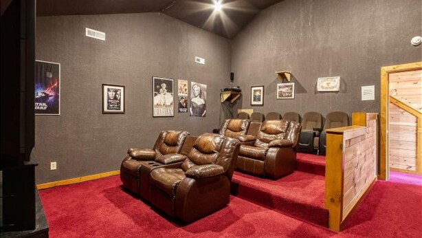A home theater room with leather recliners, a red carpet, and framed posters on the walls. - Bear Foot Lodge #308 (Sevierville)