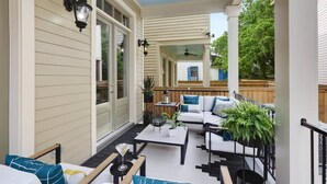 A covered patio with a white exterior, outdoor seating area, and a ceiling fan.