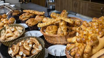 A buffet table with various breads and pastries.