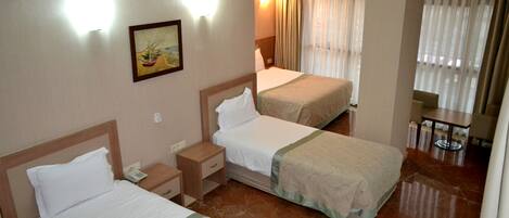 Habitación de hotel con dos camas, una mesita de noche con teléfono, un cuadro en la pared y una ventana con cortinas.