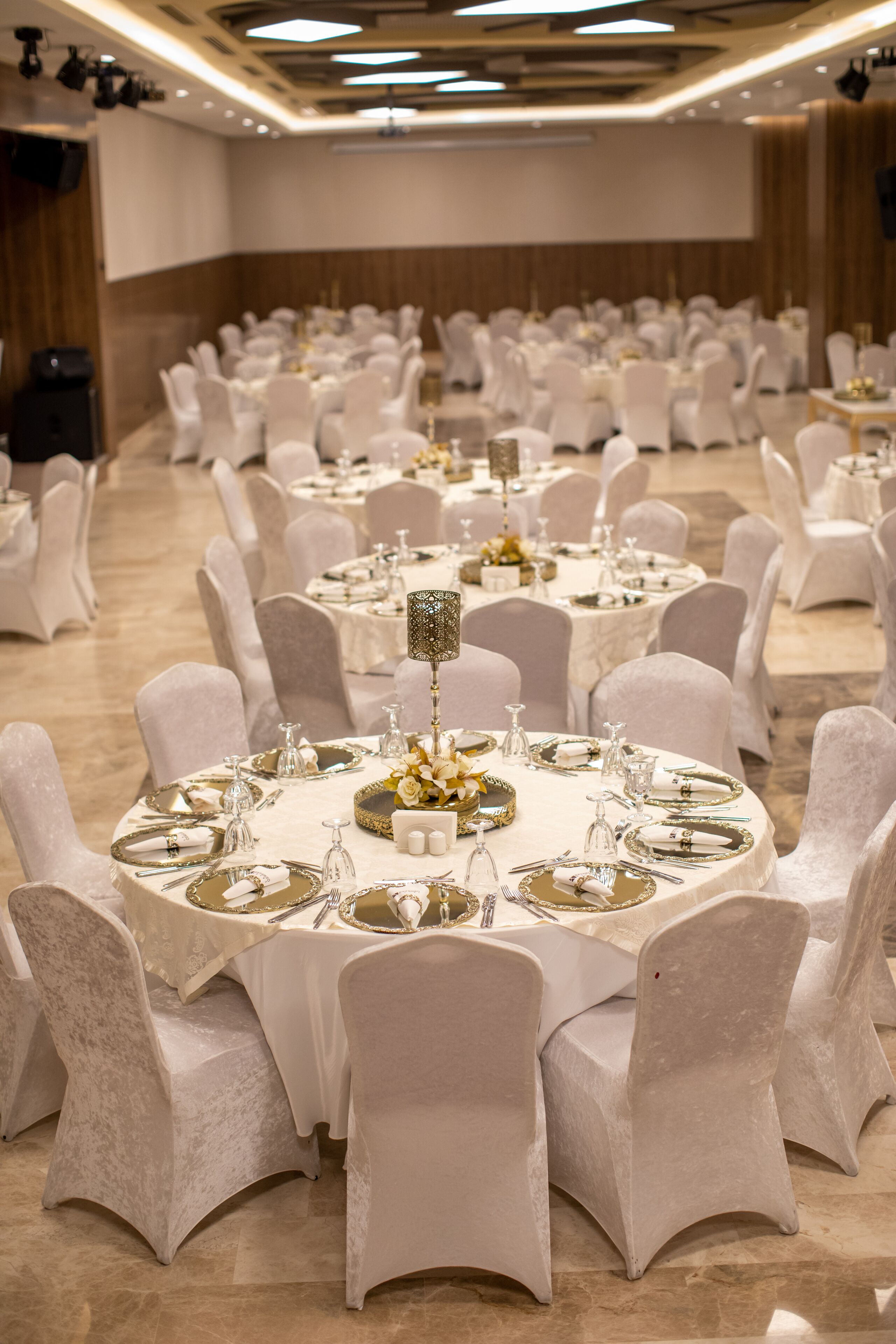 A banquet hall with round tables set for a formal event, each with white chairs and table settings.