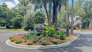 A sign for Inverness Village with a landscaped flower bed in front.