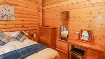 Un dormitorio de cabaña de madera con cama, cómoda, espejo y un cuadro en la pared.