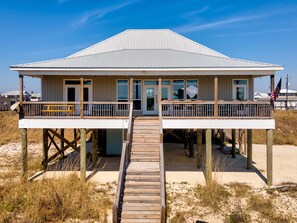 Ein Strandhaus mit einer Holzterrasse, einer überdachten Veranda und Blick aufs Meer.