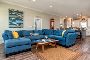 Ein Wohnzimmer mit einem blauen Modulsystem, einem Couchtisch und einem großen Wandbild mit Fischen.