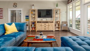 Una sala de estar con un sofá azul, una mesa de centro y un televisor.