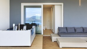 A modern living room with a sofa, a coffee table, and a view of the city through a glass door. - Skylake Penthouse - Stresa  (Stresa)