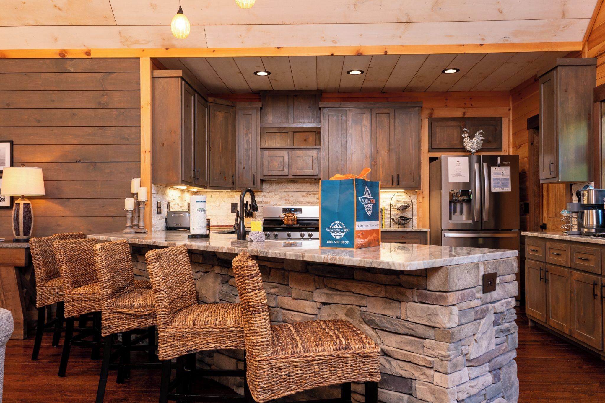 Una cucina rustica con piani in pietra, mobili in legno e un'isola integrata con sgabelli da bar.