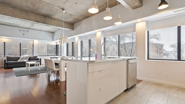 Una cocina moderna con una isla central, ventanas amplias y una zona de comedor con sofá y sillas.
