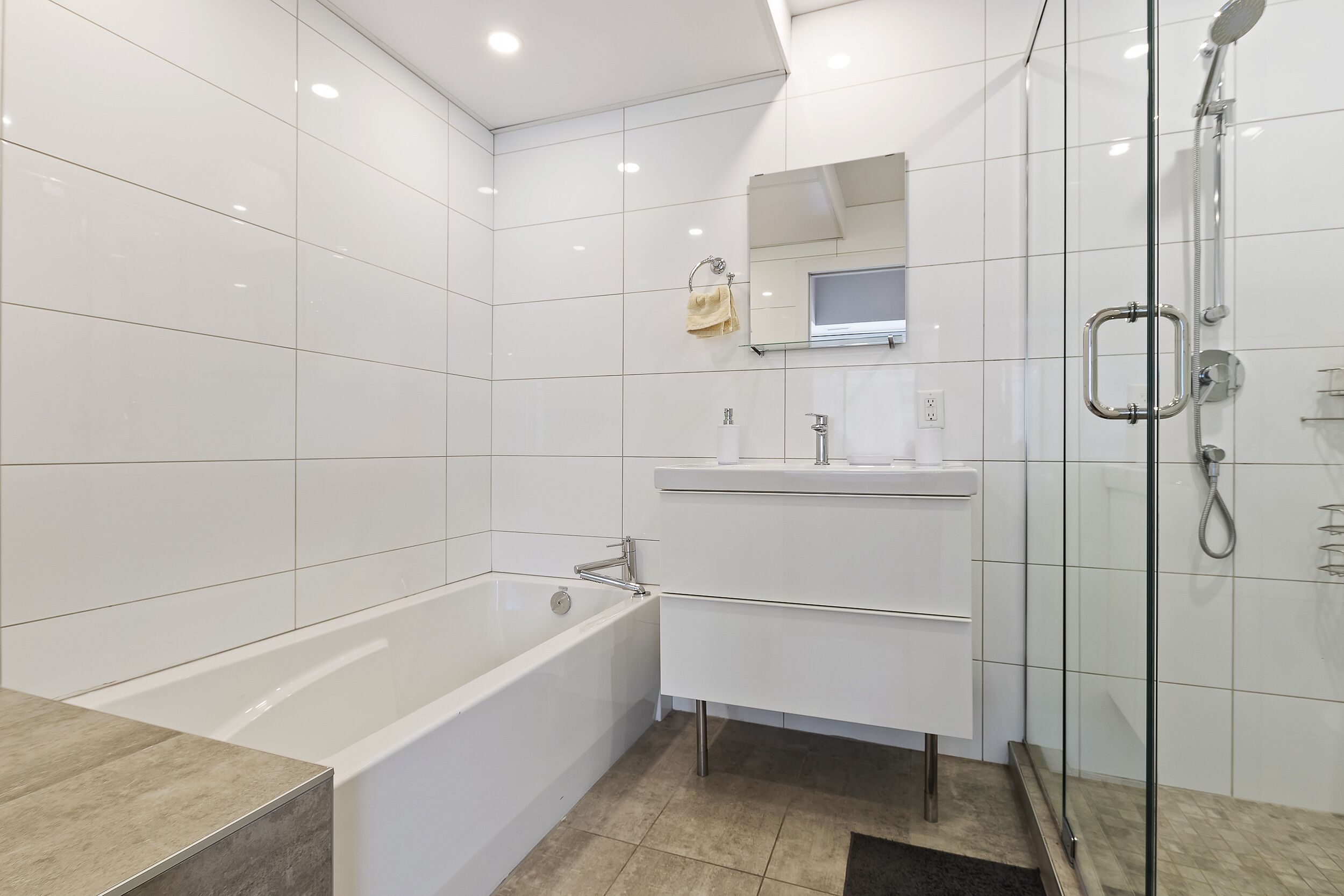 Une salle de bain moderne avec une baignoire, une cabine de douche en verre et un meuble-lavabo avec un miroir.
