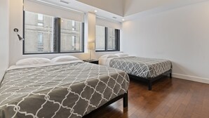 Una habitación de hotel moderna con dos camas, ventanas amplias y suelo de madera.